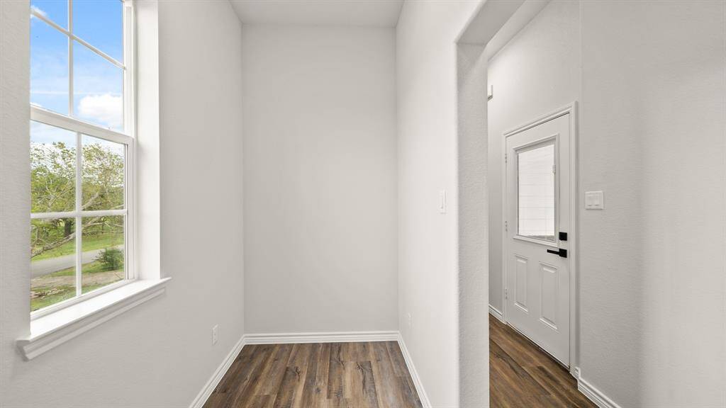 Bright space for desk with a large window, wood flooring, and a modern white door.