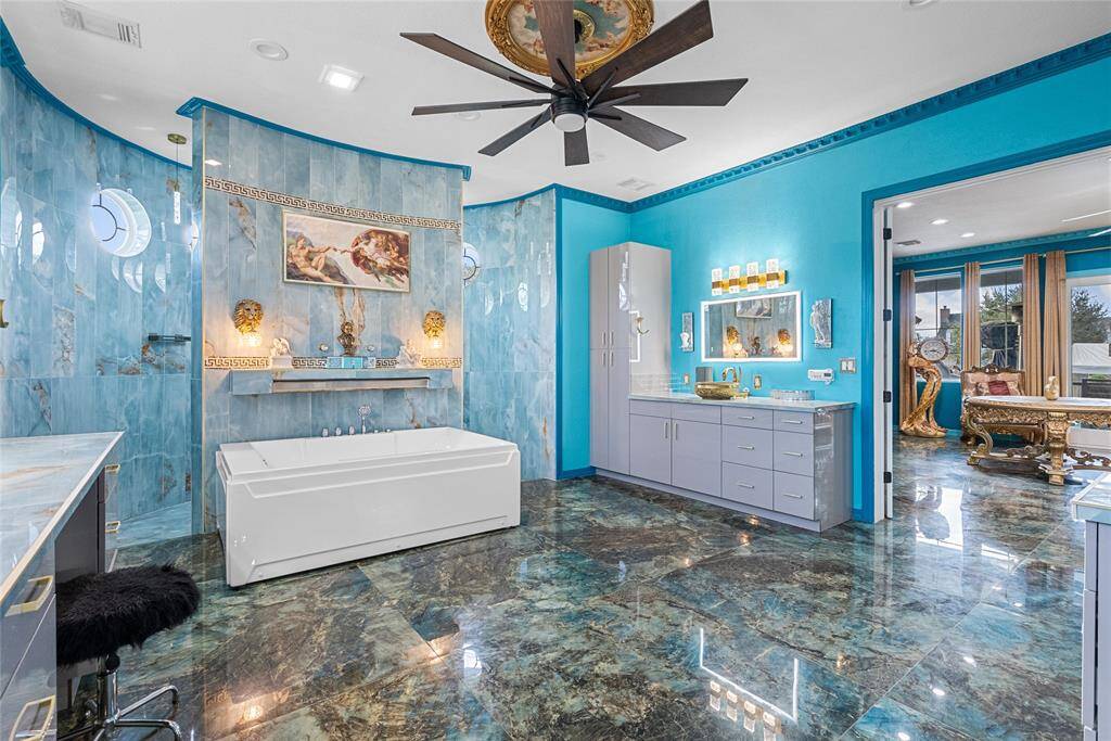 primary bathroom, features individual sinks, porcelain floors, spa tub w/waterfall, ceiling fans and lots of storage
