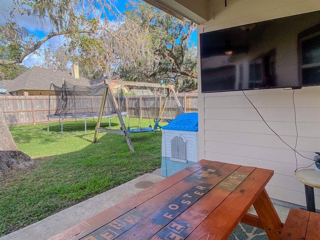 Large backyard with covered porch and shade trees