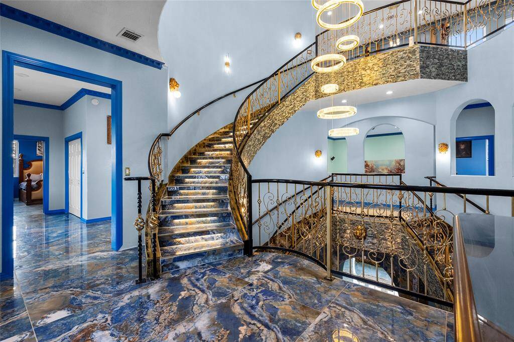 3rd floor staircase from 2nd floor landing area, lighted as you progress upward, with ultra modern chandelier. ornate handrails and mosaic tile compliment the staircase
