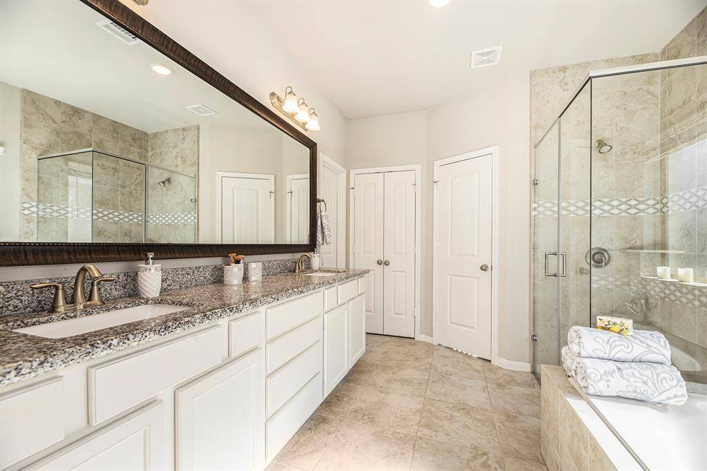 The primary en suite features double sinks, a stand-up shower with tile inlays and separate soaking tub.