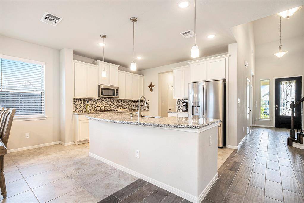 This kitchen is filled with upgrades from the bump up taller cabinets, the beautiful backspash, large farmhouse sink, pendant lighting, gorgeous granite and more!