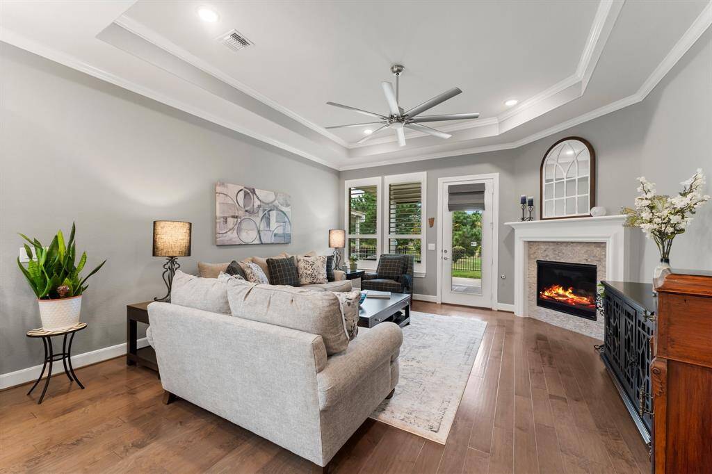Relax in your den with fireplace and serene nature views. Notice the tray ceilings.