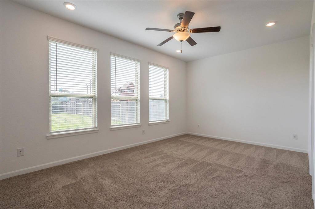 Primary Bedroom with fan, carpet that's been deep cleaned and windows with blinds that look out to the Backyard