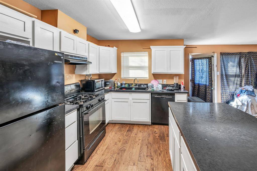 Another view of the kitchen featuring black appliances, white cabinetry, and a large island for your meal prepping! 3710 Dennis St., Houston, TX 77004
