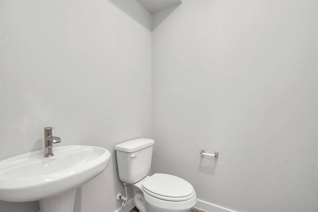 Step into this bright and airy half bath, where a sleek pedestal sink and modern hardware elevate the space with contemporary charm. Sample photo of completed home with similar floor plan. Actual colors and selections may vary.