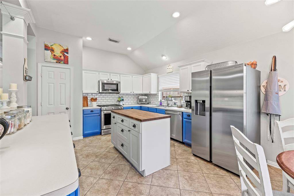 This immaculate kitchen is a chef's dream, featuring stainless steel appliances, a large center island, a charming mix of blue and white cabinetry and subway tile backsplash. With a large pantry and ample counter space, meal preparation is a breeze. With its open layout, the kitchen seamlessly flows into the dining and family areas, making it perfect for both everyday living and entertaining.