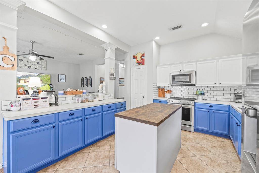 This kitchen features subway tile backsplash and freshly painted, contrasting cabinetry with vibrant blue lower cabinets and crisp white uppers. The centerpiece is a large butcher block island, perfect for meal prep and storage. Open to both the family room and dining areas, this kitchen is designed for seamless entertaining. Ample storage for all your kitchen gadgets and a large pantry ensures that everything you need is within easy reach.