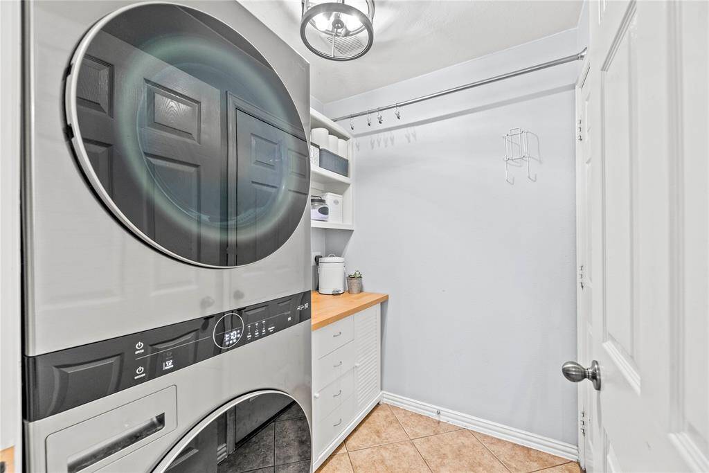 This updated utility room offers custom storage solutions, modern lighting, neutral finishes, and ample space for your full-sized stacking units.