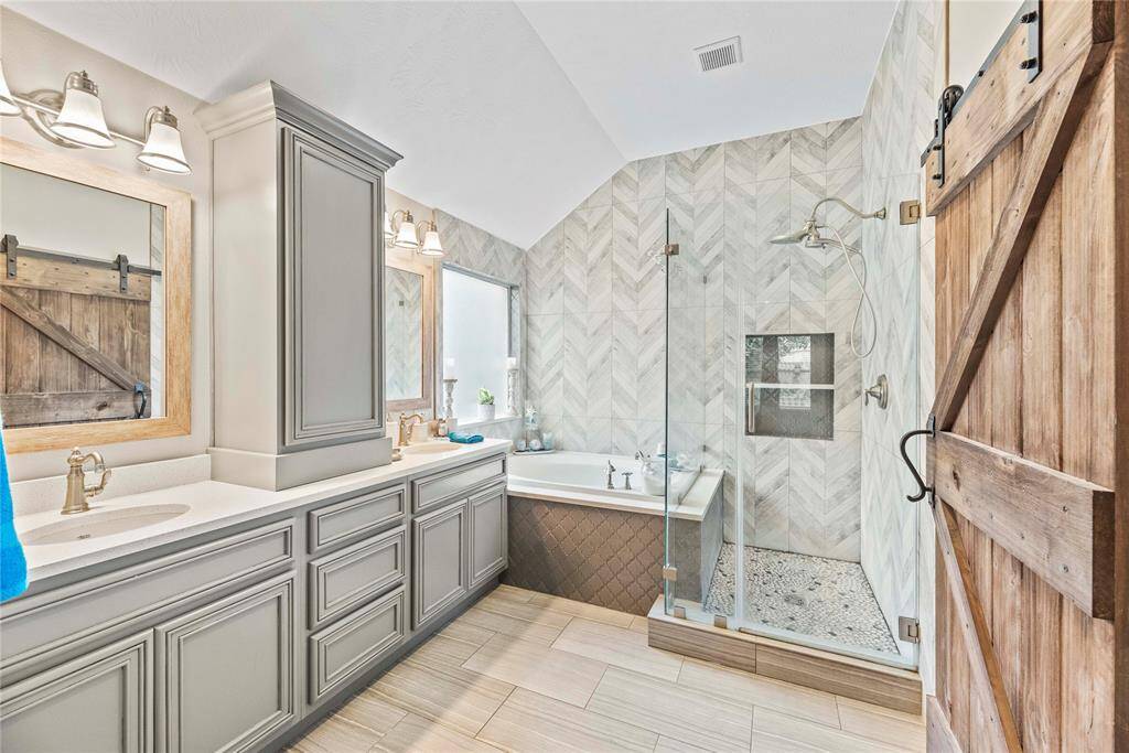 This stunning ensuite will take your breath away. Featuring a luxurious soaking tub, an oversized walk-in shower with frameless glass and elegant tile work, and a double-sink vanity with ample storage, this bathroom is the epitome of relaxation and style. The exquisite finishes and attention to detail create a spa-like retreat right in your own home. Tucked behind an impressive barn door, you will find an impressive closet.
