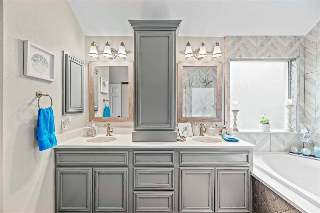 This ensuite bathroom features a beautiful dual sink vanity with custom storage solutions, ensuring plenty of space for all your essentials. The framed mirrors and elegant lighting above each sink add a touch of sophistication. With these thoughtful design elements, this bathroom is both stylish and functional, making it easy to share.