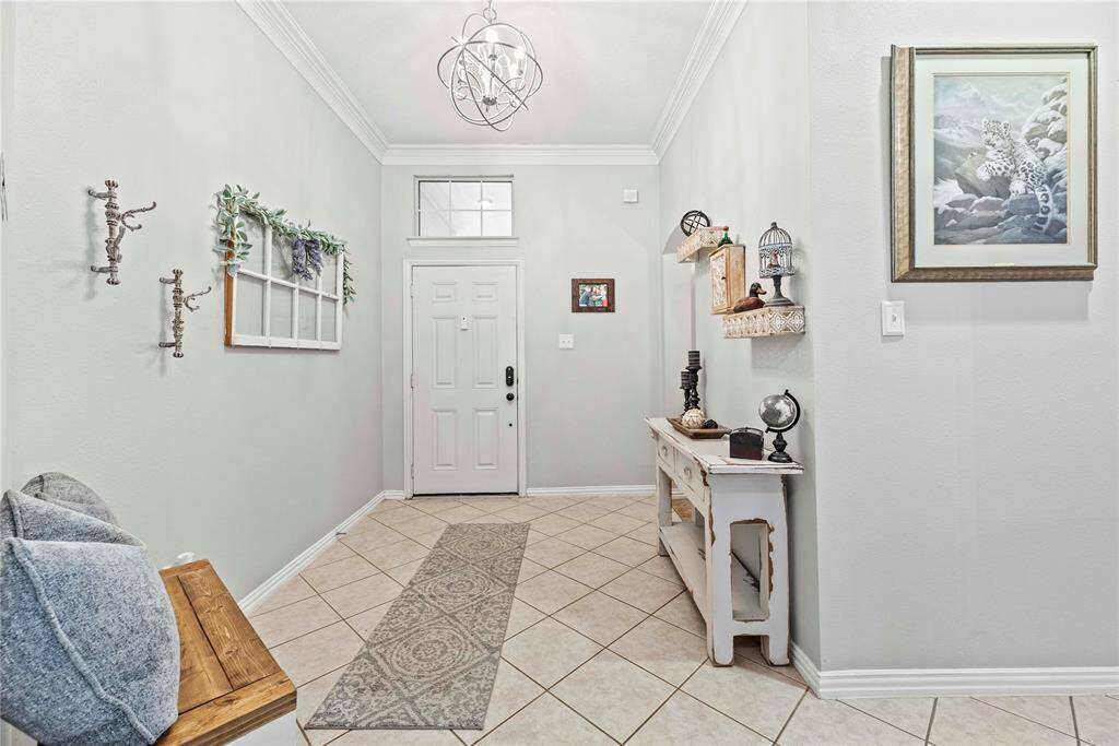 The foyer is a beautiful space to greet your guests with an elegant sphere-shaped chandelier, tile flooring, neutral paint, and previews of the spacious dining room to the left and a fabulous family room directly ahead.