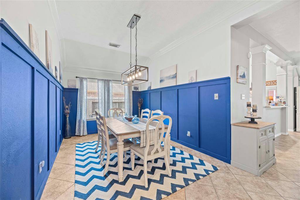 Step into the vibrant dining area, where chic lighting and bold blue accents create a striking first impression. The inviting open floor plan seamlessly connects this space to the kitchen and family room, providing the perfect space for both lavish dinner parties and casual family gatherings.