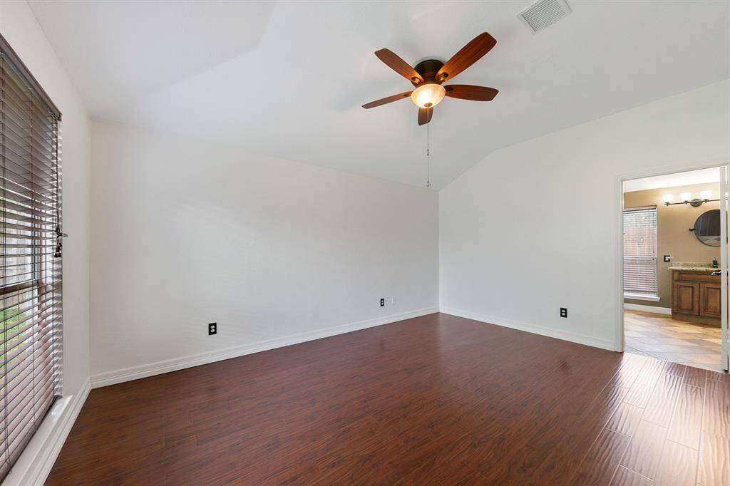 The spacious primary suite features high ceilings that enhance its airy and open feel, complemented by elegant wood floors. It includes a private ensuite, offering a serene retreat with modern finishes and ample comfort.