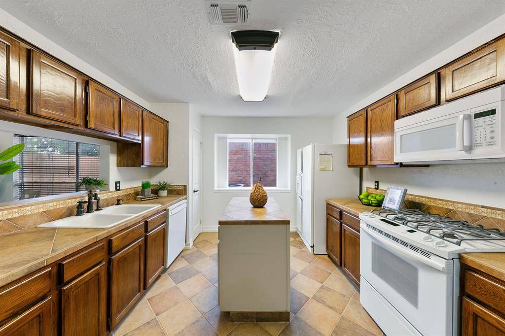 The kitchen features a functional island at its center, perfect for meal prep, a spacious pantry, and a large window that fills the space with natural light, creating a bright and welcoming atmosphere.