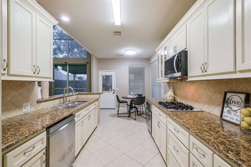 Kitchen boasts white cabinets, granite countertops, and gas range cooktop.
