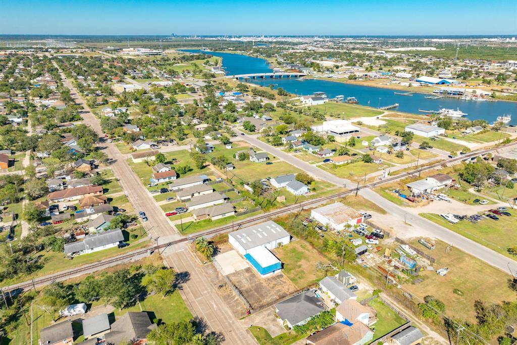 This aerial photo showcases a suburban neighborhood with tree-lined streets and single-family homes. A scenic river runs through the area, providing a picturesque view. The community appears quiet and well-maintained, with easy access to roads and nearby amenities.