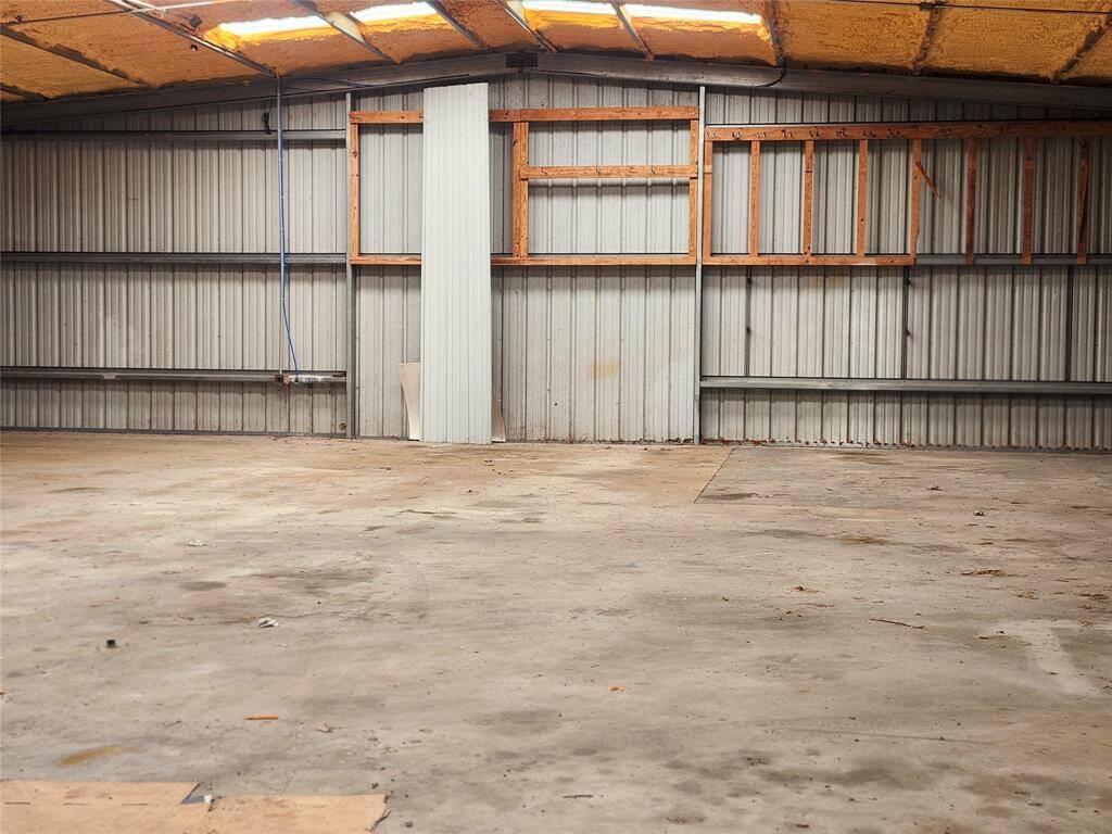 This photo shows a spacious, empty metal garage or workshop with a concrete floor and partial insulation on the ceiling, offering ample potential for storage or customization.