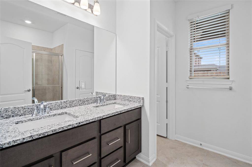 This primary bathroom is definitely move-in ready! Featuring stained cabinets with granite countertops, dual vanities, high ceilings, custom paint, sleek and dark modern finishes.