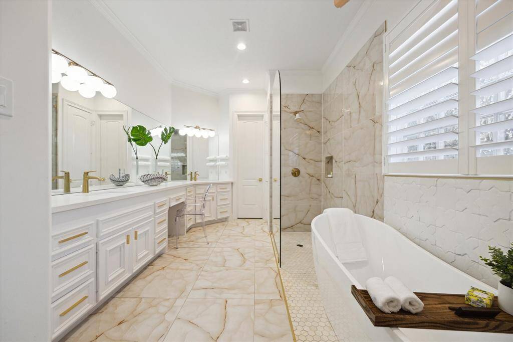 Luxurious primary bath with exquisite walk-in quartz shower, stand alone soaking tub with elegant gold fixtures.