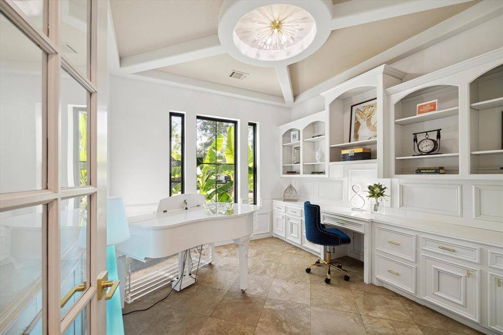 First floor study with wall of built-ins, built-in desk and decorative ceiling.