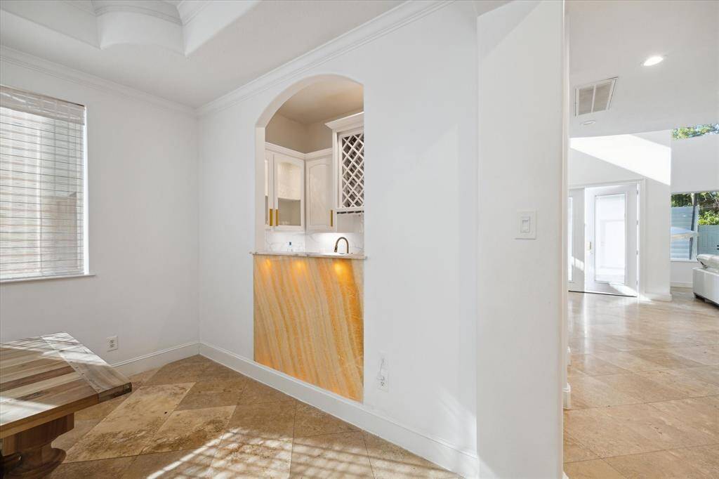 The formal dining room levels up with a back-lit onyx wall adjoining the wet bar.