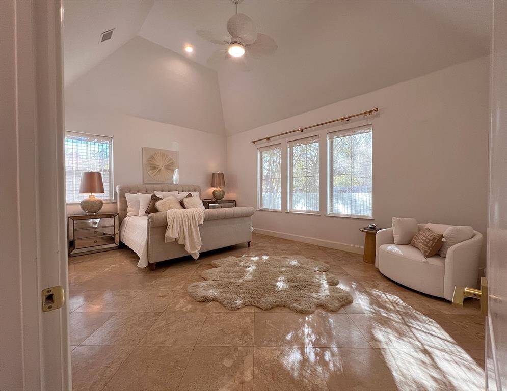 Generous size first floor primary suite with vaulted ceilings and seating area is a haven.