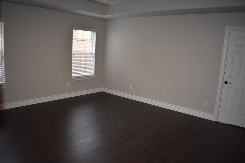 Spacious primary bedroom with abundant natural light, gleaming hardwood floors, and a new ceiling fan.