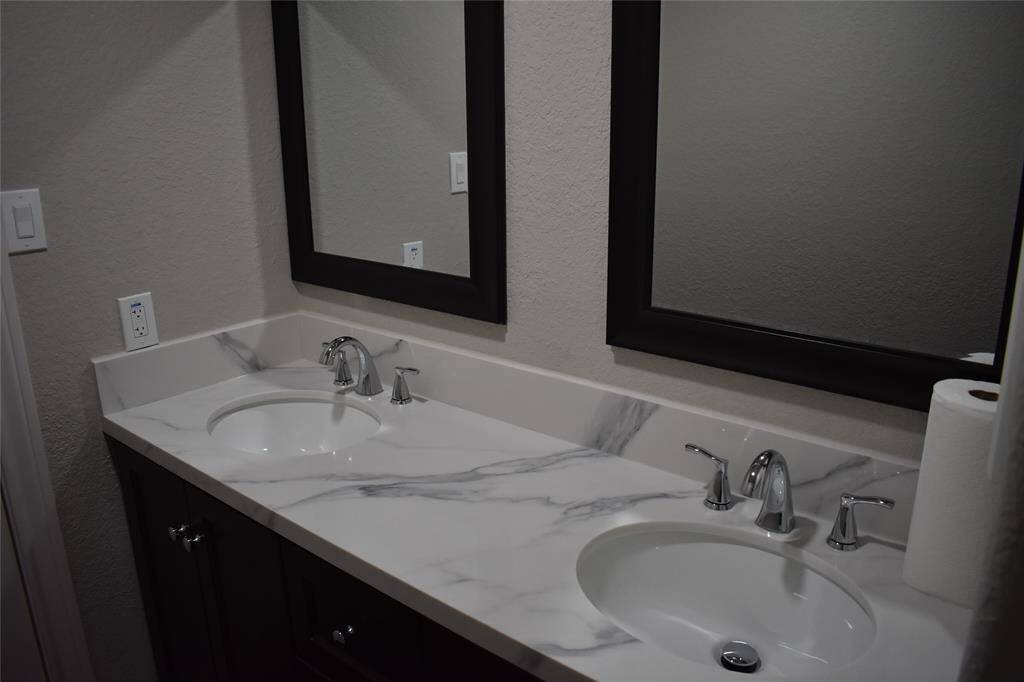 Luxurious primary bathroom featuring elegant quartz countertops and dual sinks.