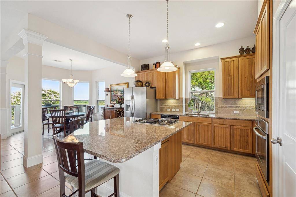 This photo highlights the kitchen’s view of the water, with large windows offering a serene and picturesque backdrop. The granite counters and wood cabinets perfectly complement the stunning natural light and scenery visible from the kitchen, making this space a peaceful place to prepare meals.