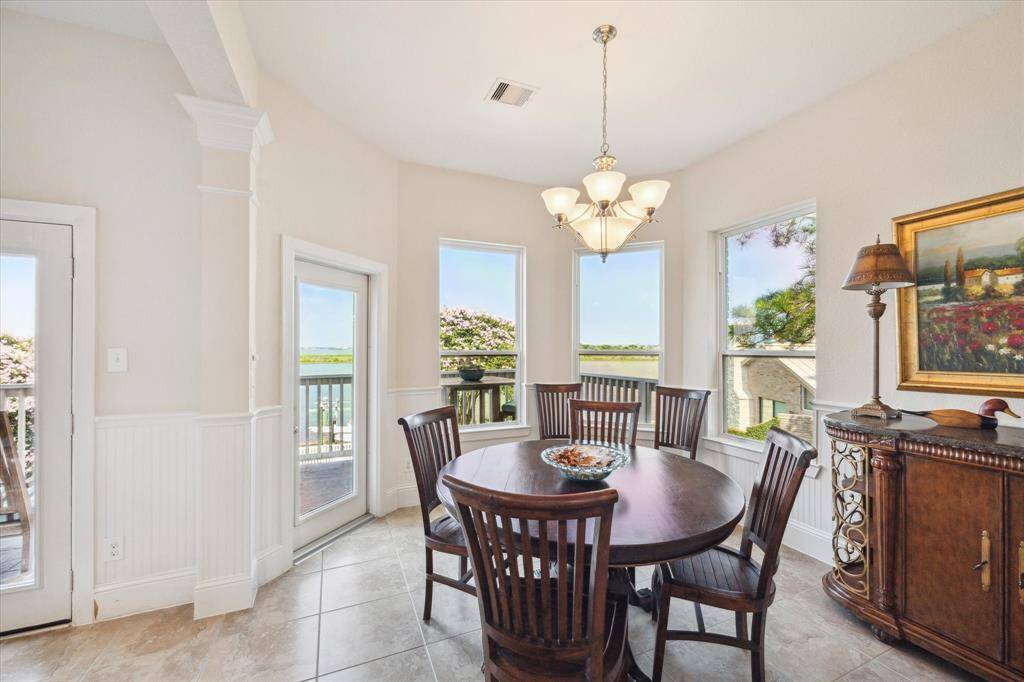The dining area is bathed in natural light from large windows that frame scenic views of the water. A charming chandelier adds elegance to the space, while the intimate dining setup makes this area ideal for both casual meals and more formal occasions.