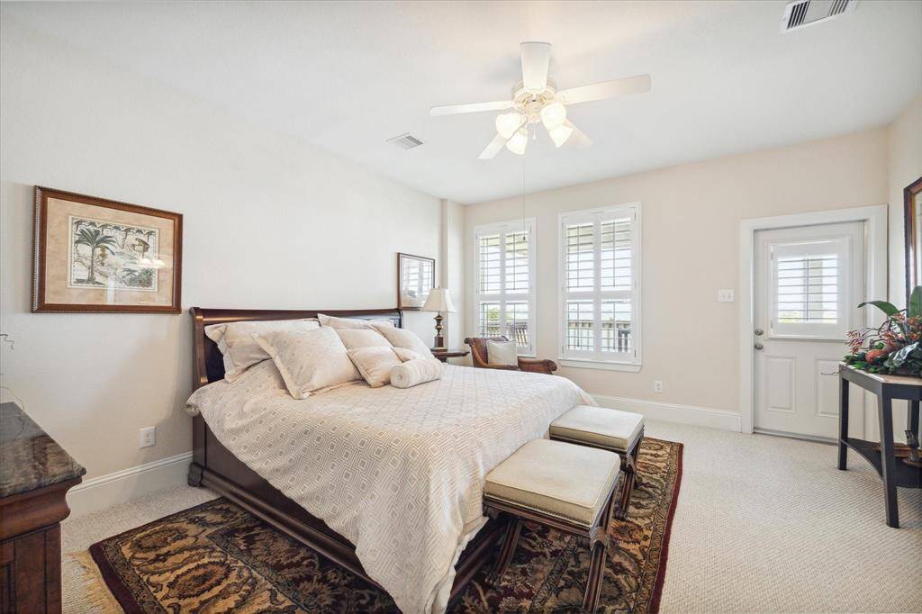 The spacious primary bedroom featuring large windows that let in natural light and provide a glimpse of the outdoor surroundings.