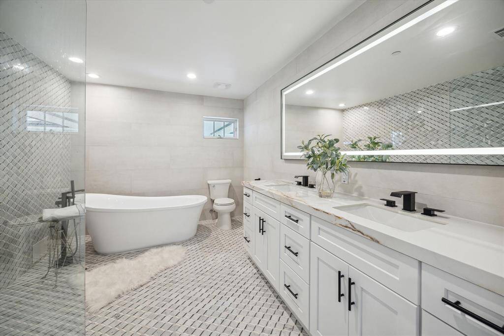 Luxurious primary bath with oversized walk in shower and separate soaking tub, dual sinks and lighted mirror.