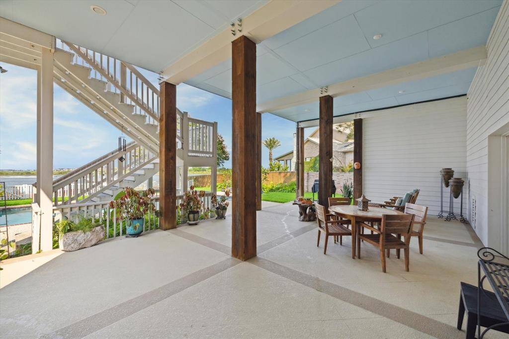 Experience outdoor living at its finest under this spacious covered patio with charming coastal details and serene water views. Featuring sturdy wooden columns and a beautiful staircase leading to the upper levels, this area is ideal for alfresco dining, entertaining, or simply relaxing while taking in the tranquil surroundings.