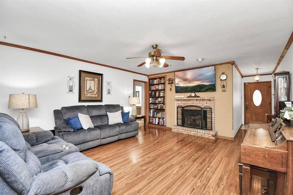 A cozy and inviting living room featuring beautiful hardwood floors and a charming fireplace, perfect for creating a warm, relaxed atmosphere. The space is ideal for both quiet nights in or entertaining guests, with ample room for seating and natural light pouring in from large windows. The fireplace adds a touch of elegance and comfort, making this the perfect spot to unwind.