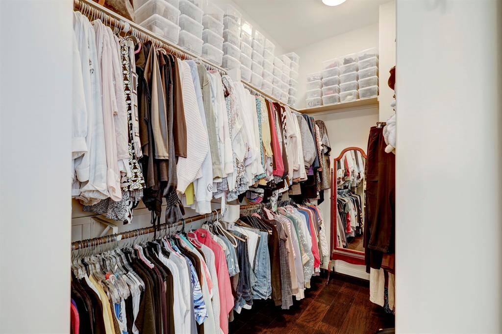 Spacious walk-in closet with ample hanging space, shelves with organized storage bins, and a full-length mirror. Ideal for maximizing clothing organization.