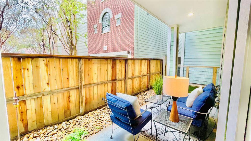 This inviting living space features elegant French doors opening to a charming balcony, perfect for relaxation. The room boasts rich wood floors, a modern accent wall, and ample natural light, creating a warm and welcoming atmosphere.