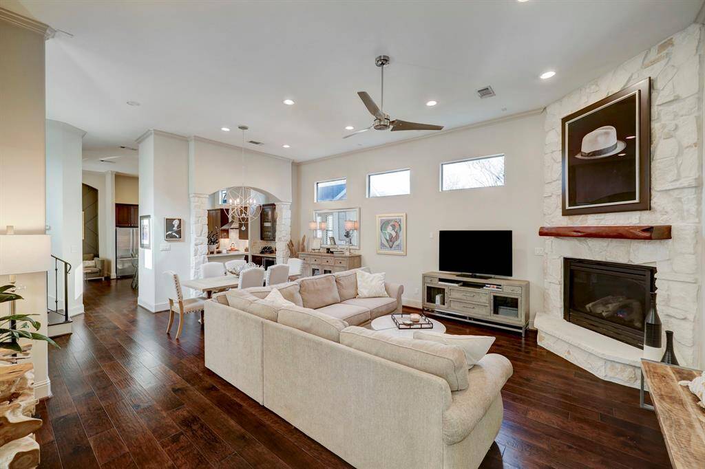 This spacious living area features hardwood flooring, a cozy stone fireplace, and ample natural light. It seamlessly connects to the dining and kitchen areas, providing an open and inviting atmosphere perfect for entertaining.