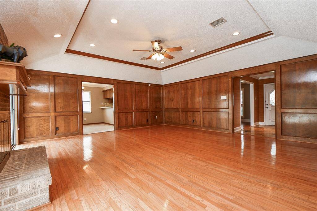 Spacious and inviting family room featuring rich wood paneling, elegant hardwood floors, and ample natural light, perfect for gatherings and relaxation.