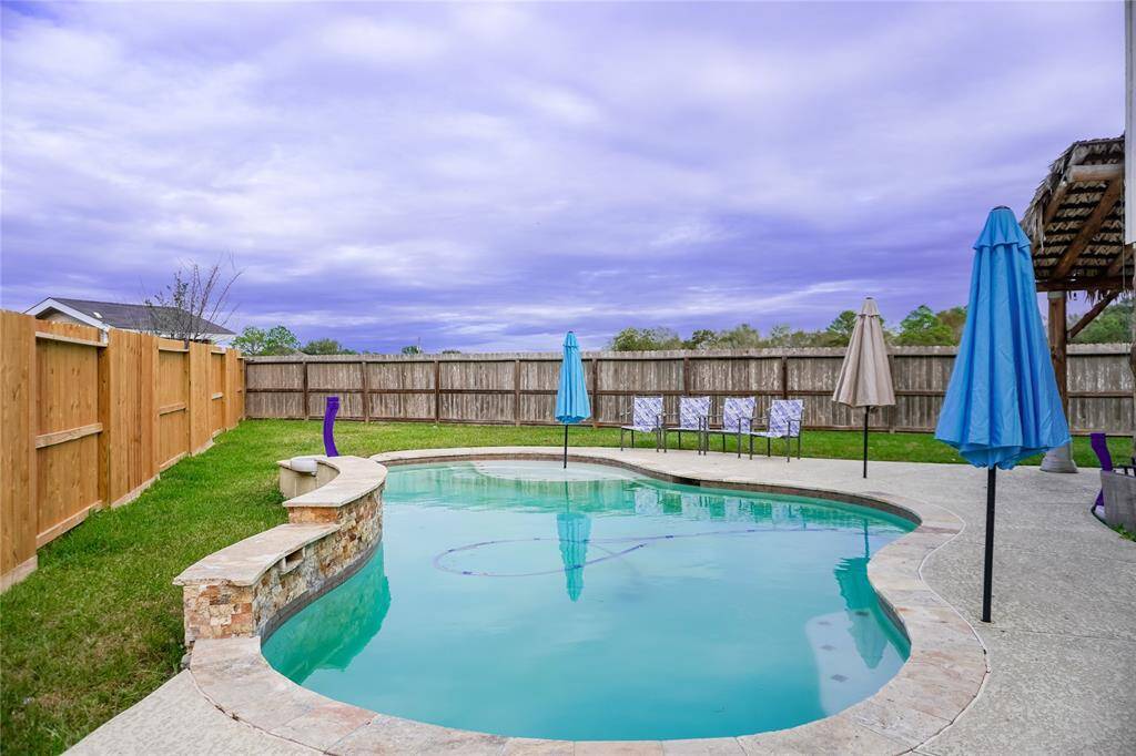 This backyard features a private swimming pool with a stone edge, surrounded by a new fence for privacy, making it ideal for relaxation and entertaining.