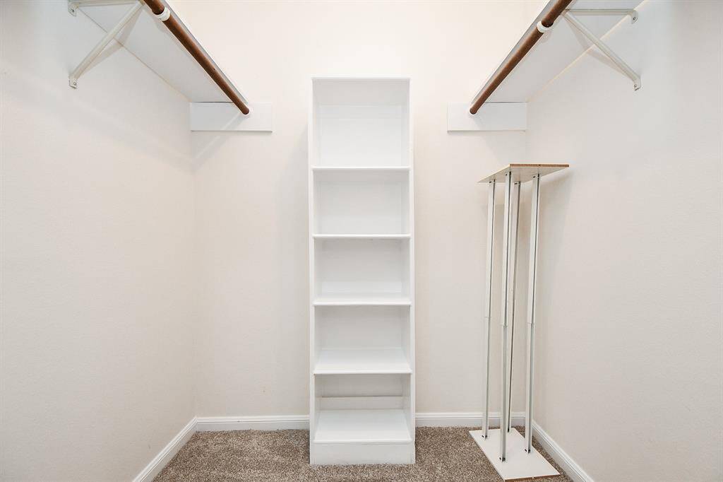 Spacious walk-in closet featuring ample shelving and dual hanging rods for optimal organization.