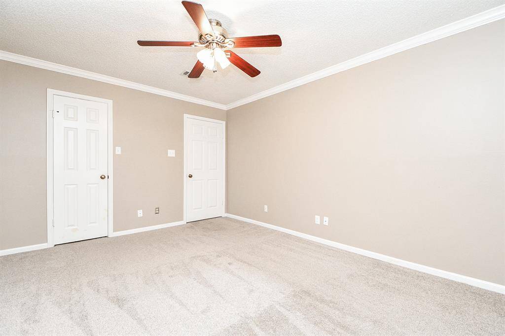 Cozy secondary bedroom with neutral tones, plush carpeting, and a ceiling fan for comfort.