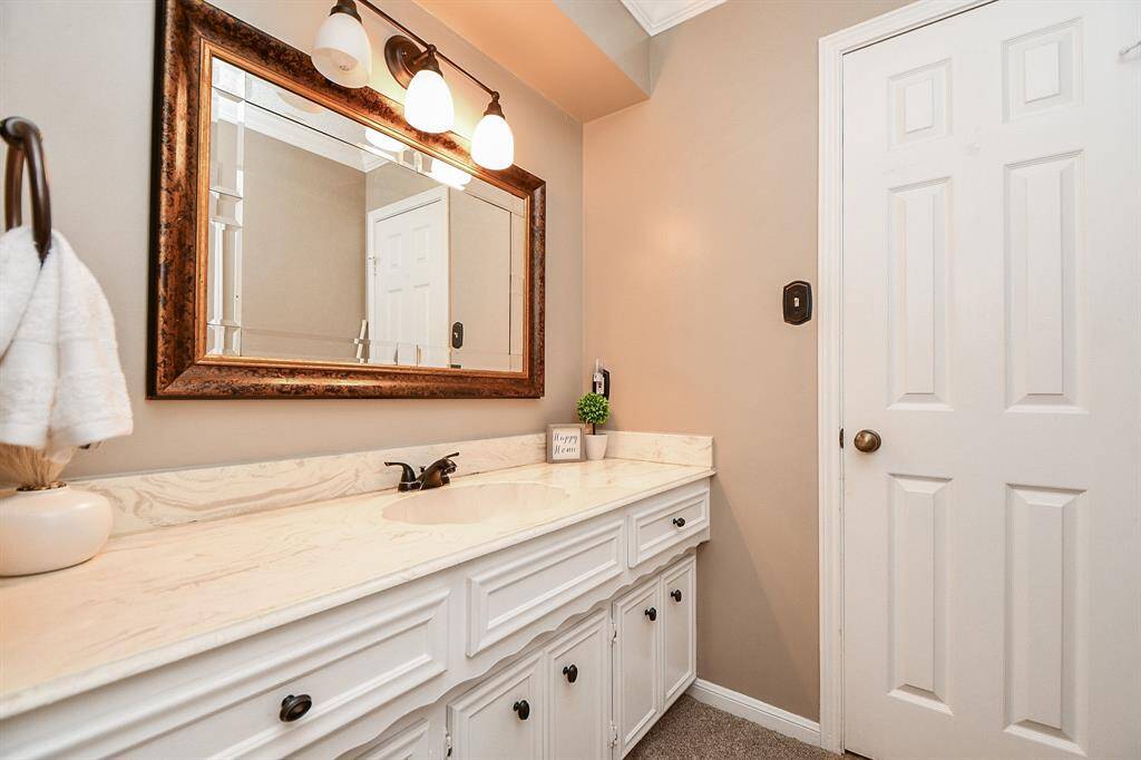 Elegant bathroom featuring a spacious vanity with ample storage, a stylish framed mirror, and warm lighting for a cozy ambiance.