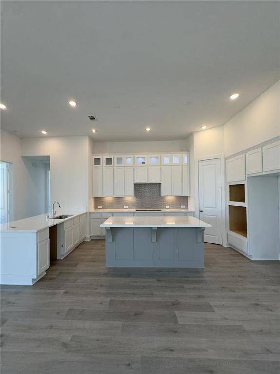 HOME IN PROGRESS - A gourmet kitchen featuring under cabinet lighting, upgraded stacked upper cabinets with glass inserts and puck lights, and a sleek 5-burner gas cooktop!