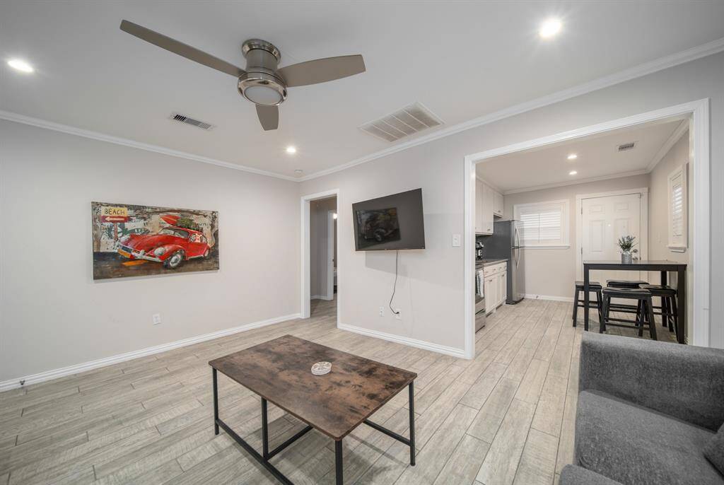 A wide doorway leads to the adjacent kitchen. The narrower doorway on the left leads to two bedrooms and a shared bath.