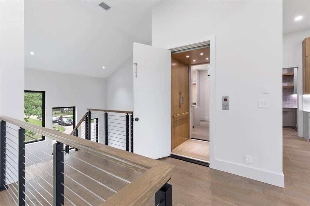 View of the second story landing with an elevator that also opens into the primary closet. The kitchen is on the right.