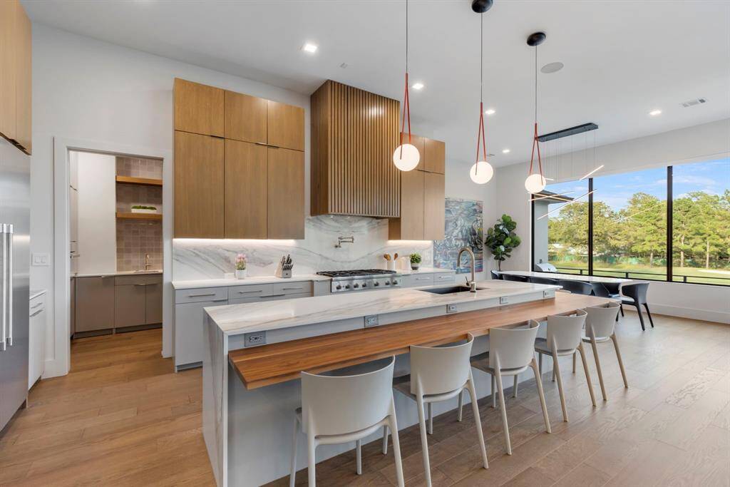 View of the kitchen with custom-made quartz/ walnut island countertop with a waterfall edge and seating for six.