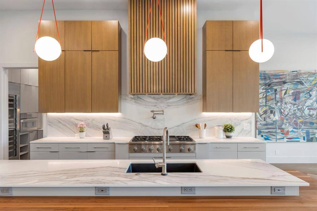 Another view of the island and back countertop with book-matched quartz and pot filler with Thermador gas cooktop.