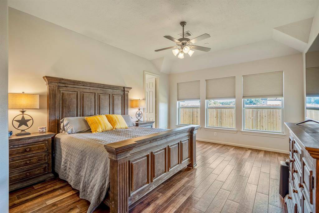 The primary bedroom features a spacious layout with hardwood floors, large windows that flood the room with natural light, and is pre-wired for a sound system, making it a perfect blend of comfort and modern convenience.