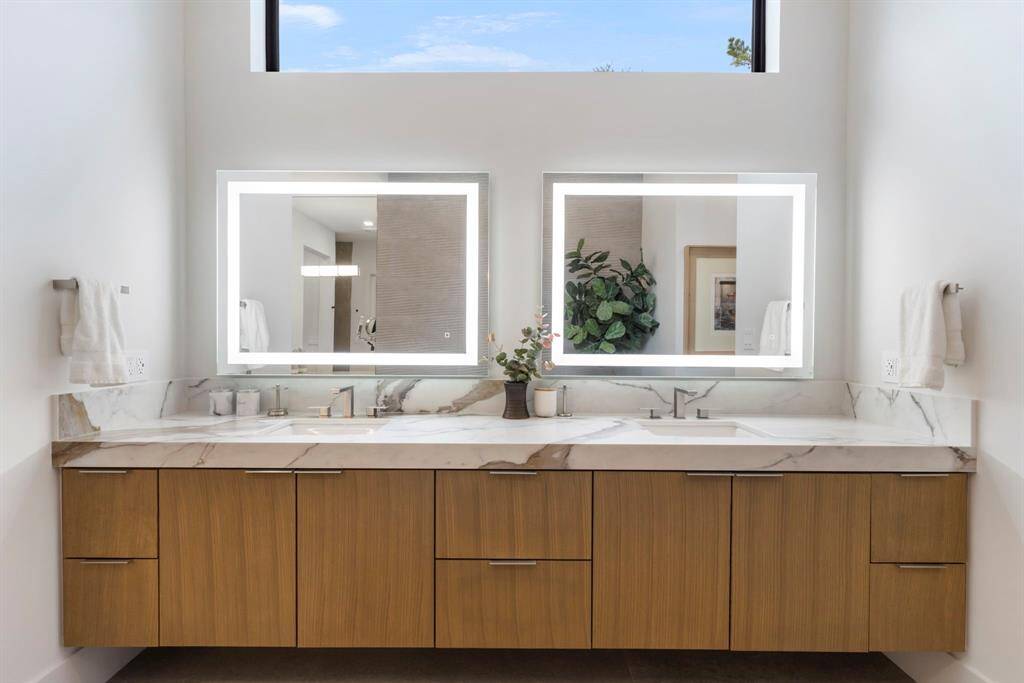 The primary bathroom has dual vanity sinks with LED mirrors.  The floating cabinets have electrical outlets for all your accessories.  The 96" x 18" window allows lots of natural light.
